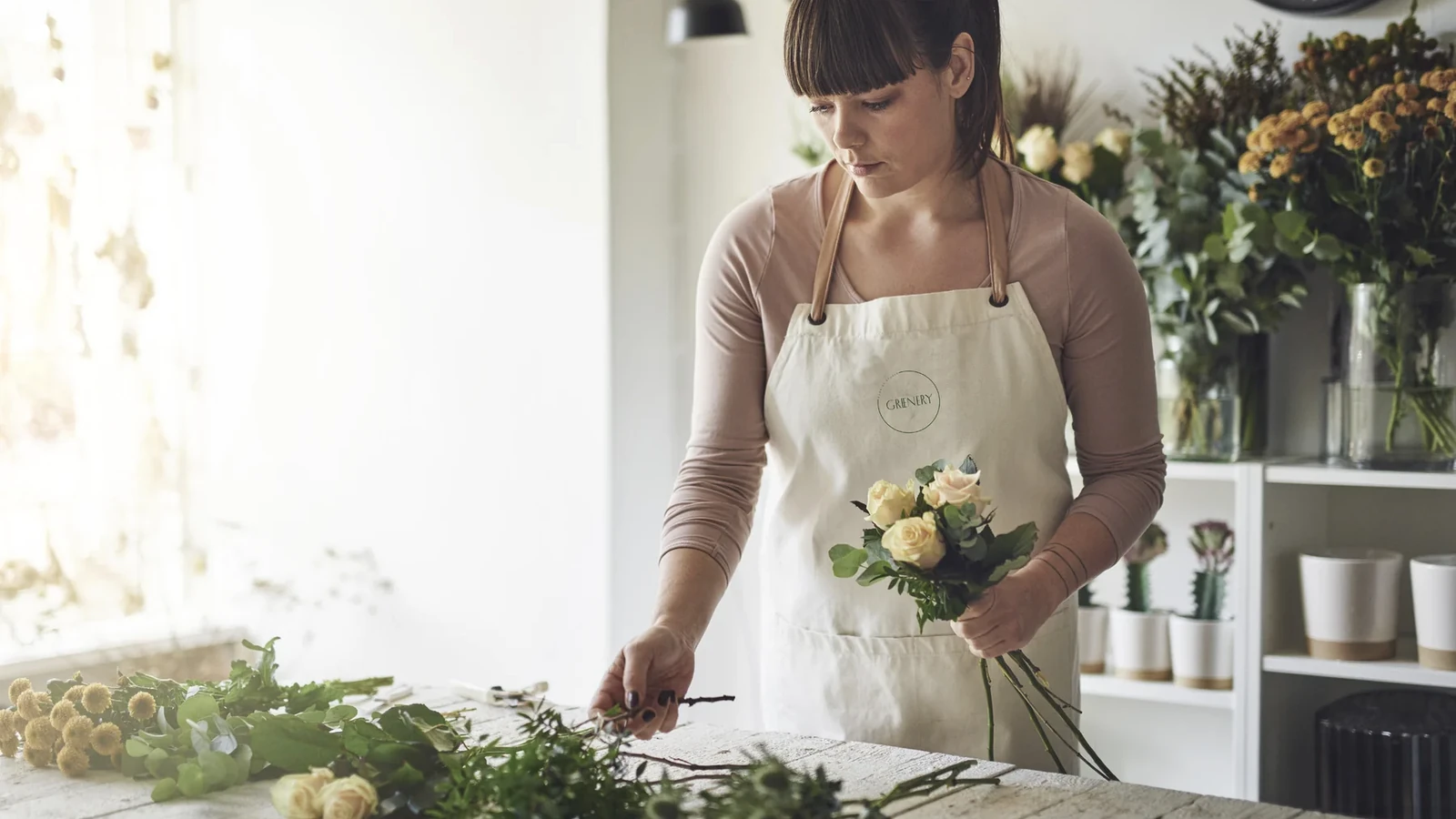 Greenery florist preparing flowers in a branded studio apron