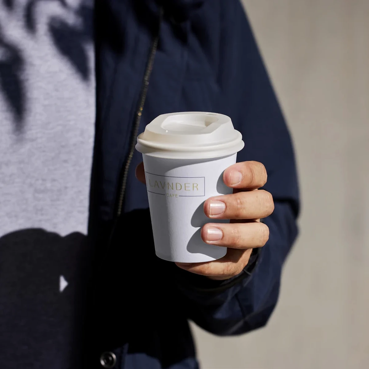 Lavnder café branded takeaway coffee cup held outdoors